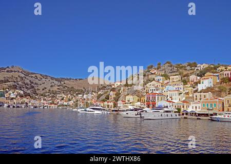 Grecia, isola di Symi: Vista del porto, con una variegata gamma di facciate classiche sul pendio terrazzato, che scende fino al lungomare. Foto Stock