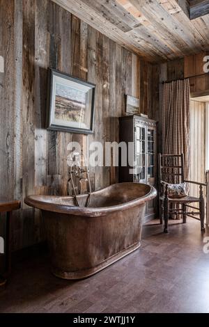 Bagno rustico indipendente in ottone con pareti rivestite in legno in un hotel di lusso ad Ardfin, sull'Isola di Giura, Ebridi interne, Scozia, Regno Unito Foto Stock