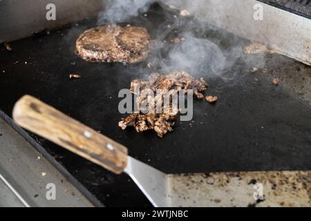 Schwabmünchen, Baviera, Germania - 17 marzo 2024: Bistecca Philly e hamburger su una griglia calda. Preparazione di un Philly Cheesburger *** Philly Steak Fleisch und Burger Patty auf einem heißen Grill. Zubereitung von einem Philly Cheesburger Foto Stock