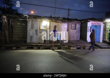 La gente del posto torna a casa dal lavoro lungo le strade trafficate di Kibera Slum, Nairobi. Kibera, il più grande slum di Nairobi e Africa, è hom Foto Stock