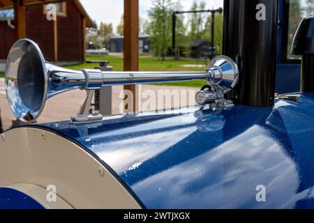 Primo piano del clacson vintage in acciaio su un'auto blu nel parco, attenzione selettiva Foto Stock