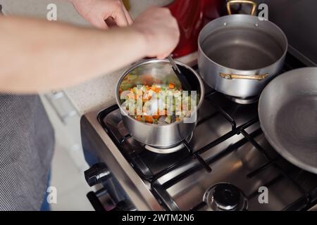 Preparazione di verdure fresche per la cottura su un piano cottura a gas Foto Stock