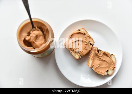 Pasta di noci spalmata su un pezzo di pane su un piatto Foto Stock