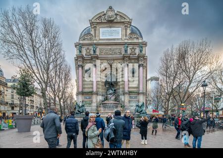 I turisti si riuniscono intorno all'iconica Fontana di Saint Michel a Parigi durante la serata. Foto Stock