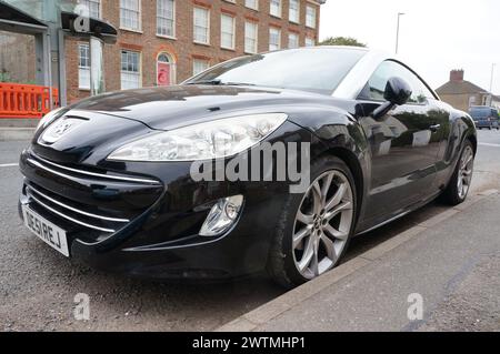 Un'auto sportiva nera Peugeot RCZ parcheggiata per strada Foto Stock