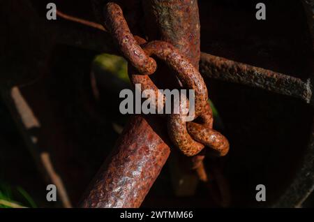 Primo piano di una catena arrugginita che fissa una vecchia macchina per motivi di sicurezza Foto Stock