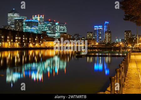 Molo Groenlandia al tramonto, Surrey Quays, Londra Regno Unito, con edifici di Canary Wharf illuminati e riflessi nell'acqua Foto Stock