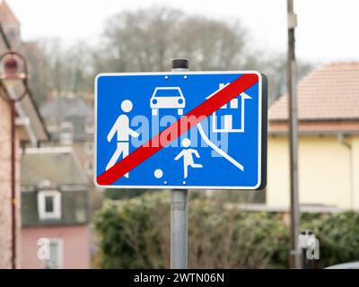 Fine di un cartello stradale vivo in un quartiere residenziale. Simbolo del traffico quando si lascia un'area con bambini che giocano sulla strada. Fine della zona del limite di velocità Foto Stock