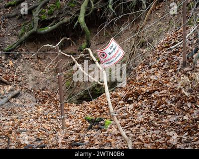 Entrata crollata di una vecchia miniera con un cartello di pericolo "Lebensgefahr - Betreten verboten!" (Pericolo per la vita - nessun disprezzo) in una foresta in Germania. Foto Stock