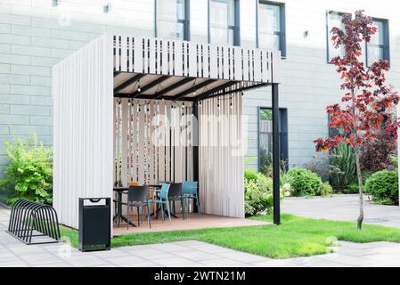 Moderna zona fumatori all'esterno. edificio business, gazebo in legno con sedie. Zona verde. Moderno business center. Foto Stock