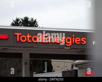 Insegna con il logo TotalEnergies all'esterno di un edificio di un distributore di benzina. Pubblicità illuminata della compagnia elettrica e energetica francese. Foto Stock