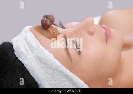 Procedura cosmetologica. Bella giovane donna con una lumaca ahatin sul viso in un salone di bellezza. Foto Stock