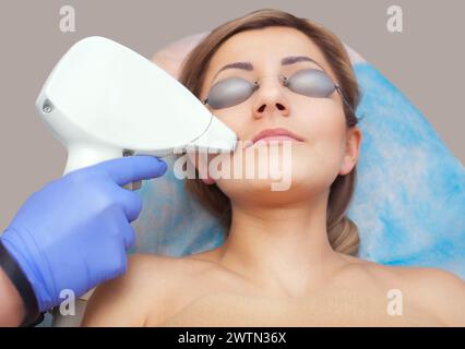 Il cosmetologo esegue la procedura di epilazione laser sul viso Foto Stock