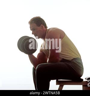 Giovane uomo in abbigliamento sportivo in studio. Sollevamento pesi. Foto Stock