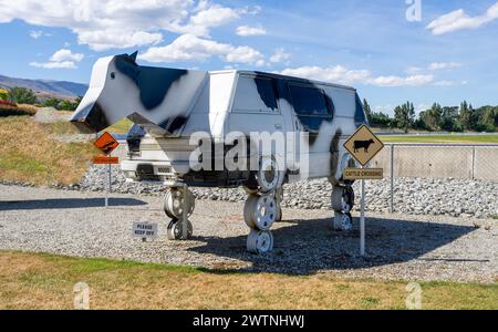 Cromwell, nuova Zelanda- 3 gennaio 2024: Una scultura ibrida di una mucca e di un'auto bianca su ruote, sotto un cielo blu a Highlands Park, Cromwell, nuova Zelanda Foto Stock