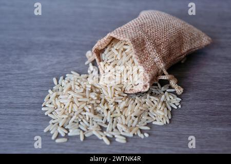 Immagine ravvicinata del riso integrale in un piccolo sacco di bavaglia su un tavolo di legno con spazio per copiare. Foto Stock