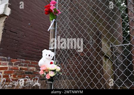 Philadelphia, Stati Uniti. 18 marzo 2024. Orso di Teddy e memoriale dei fiori allestito su una recinzione sulla scena in cui i resti umani di un bambino decomposto sono stati trovati in un borsone in un vicolo di Philadelphia. Intorno alle 9:50 la polizia rispose al blocco 600 di North 38th Street, lunedì mattina. La polizia è stata accolta da un uomo che stava lavorando nel retro della proprietà e il maschio ha indirizzato gli agenti di polizia a un borsone che conteneva i "resti gravemente decomposti di un bambino". In questo momento, il sesso è sconosciuto. Credito: SOPA Images Limited/Alamy Live News Foto Stock