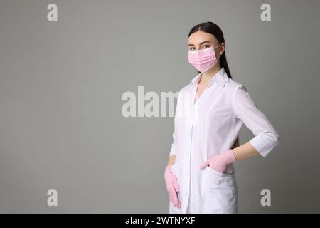 Cosmetologo in uniforme medica su sfondo grigio, spazio per il testo Foto Stock