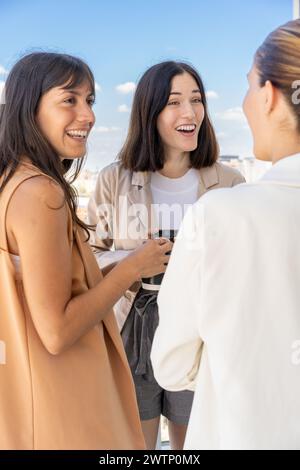 Tre colleghi d'affari si stanno gustando il caffè e condividendo un momento di cameratismo fuori dall'ufficio Foto Stock