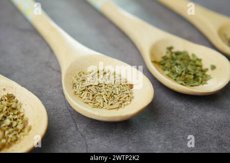 Quattro cucchiai di legno che reggono varie spezie su un tavolo Foto Stock