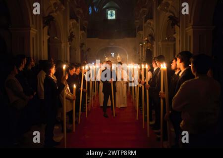 Malaga, Spagna. 18 marzo 2024. I penitenti della fratellanza "Humildad" sono visti tenere le candele mentre prendono parte al trasferimento cloistrale della statua di Cristo al suo galleggiante all'interno della chiesa del Santuario de la Victoria, prima dell'inizio della settimana Santa della domenica delle Palme. Durante le ultime settimane decine di confraternite portano le loro icone nelle loro chiese, seguendo i rituali tradizionali circondati dalla luce delle candele. Credito: SOPA Images Limited/Alamy Live News Foto Stock