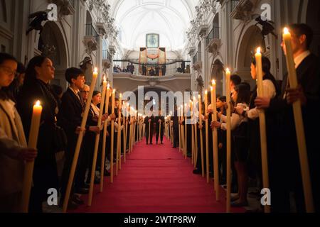 Malaga, Spagna. 18 marzo 2024. I penitenti della fratellanza "Humildad" sono visti tenere le candele mentre prendono parte al trasferimento cloistrale della statua di Cristo al suo galleggiante all'interno della chiesa del Santuario de la Victoria, prima dell'inizio della settimana Santa della domenica delle Palme. Durante le ultime settimane decine di confraternite portano le loro icone nelle loro chiese, seguendo i rituali tradizionali circondati dalla luce delle candele. Credito: SOPA Images Limited/Alamy Live News Foto Stock