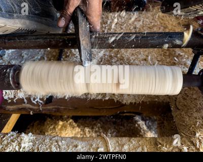 Falegname che forma un pezzo di legno con tornitura e tornio che volano via trucioli ad alta velocità Foto Stock