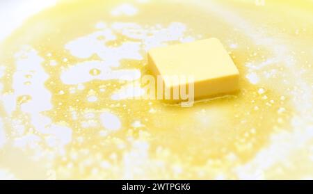 Un pezzo di burro fuso sulla padella Foto Stock