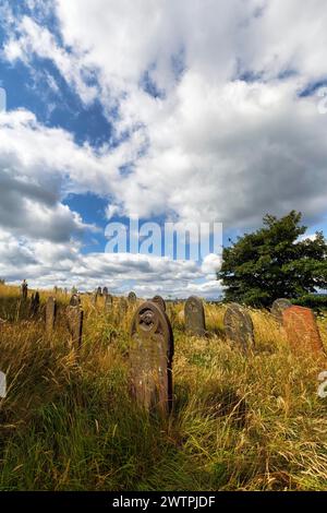 Vecchie lapidi in un prato, file di tombe in un cimitero, St Garmons Church, Capel Garmon, Conwy, Galles, Regno Unito Foto Stock