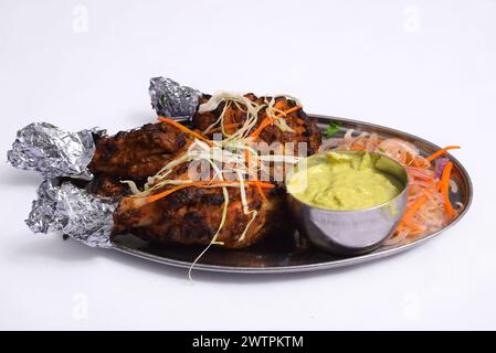 I kabab di Tangdi sono pollo alla griglia preparato con cosce di pollo, spezie, yogurt e panna. Serviti su un piatto con chutney verde guarniti con cipolle. Foto Stock
