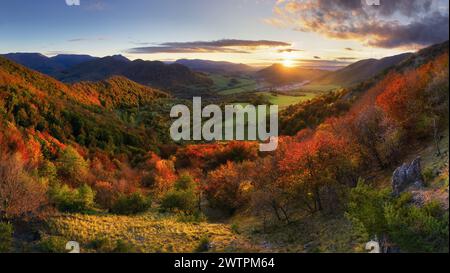 Montagne al tramonto in Slovacchia. Paesaggio con colline di montagna alberi di arancio ed erba in autunno, cielo colorato con raggi di sole dorati. Panorama Foto Stock