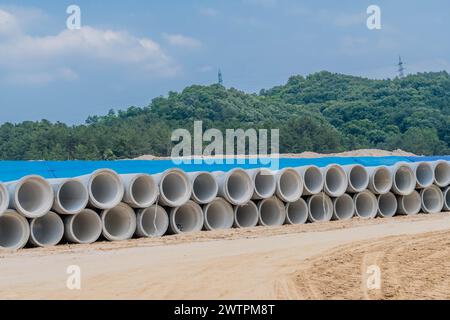 Pile di grandi tubi di cemento ricoperti di telone blu nel cantiere vicino a una strada sterrata, a Daejeon, Corea del Sud, Asia Foto Stock