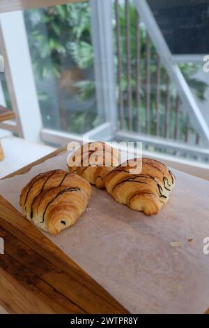 Focalizzata su croissant appena sfornati su un tavolo di legno. Concetto di alimentazione sana e dolce. Deliziosa colazione francese. Foto Stock