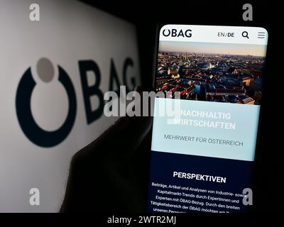 Persona che detiene un cellulare con pagina web della società austriaca Österreichische Beteiligungs AG (ÖBAG) con logo. Messa a fuoco al centro del display del telefono. Foto Stock