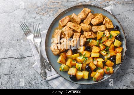 Piatto portoghese Rojoes Minhota di cubetti di maiale fritti con contorno di patate primo piano sul piatto sul tavolo. Vista dall'alto orizzontale Foto Stock