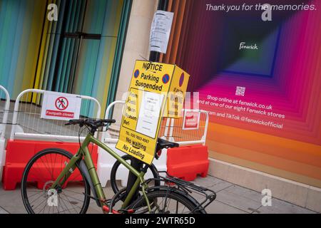 Una bicicletta è chiusa a chiave su un palo dove un avviso di sospensione del parcheggio è apposto fuori dal grande magazzino Fenwicks, recentemente chiuso, in New Bond Street, il 18 marzo 2024, a Londra, Inghilterra. Foto Stock