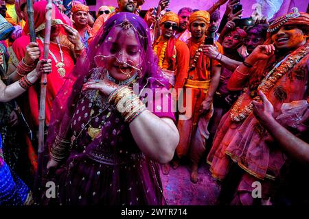 Una donna devota canta di fronte ai devoti maschi come da rituale tradizionale di Lathmar Holi. Il festival Lathmar Holi si basa su una leggenda indù, secondo la quale Lord Krishna viaggiò dal suo villaggio natale di Nandgaon a Barsana per prendere in giro il suo amante Radha. Radha e il suo entourage si sono offesi per le sue avances e hanno cacciato Krishna dal villaggio. Oggi la leggenda è celebrata al tempio Radha Rani di Barsana. Ogni anno, gli uomini di Nandgaon viaggiano a Barsana, dove vengono accolti da donne che brandiscono lathis (bastoni). I festeggiamenti durano più di una settimana in cui i partecipanti gettano colore Foto Stock