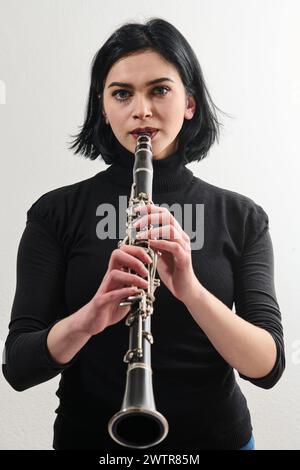 Graziosa bruna musicista che posa con Clarinetto su sfondo bianco Foto Stock