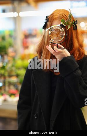 una ragazza sceglie ed esamina i germogli di piante in un negozio Foto Stock