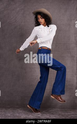 Abiti da donna, moda e western in studio, stile selvaggio West e country su modello indiano. Una donna forte e sicura di sé con un cappello alla moda Foto Stock