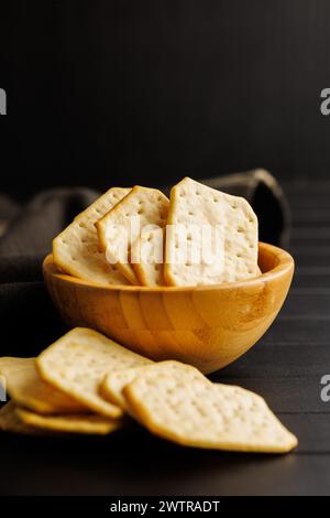 Cracker salati in una ciotola su sfondo scuro Foto Stock