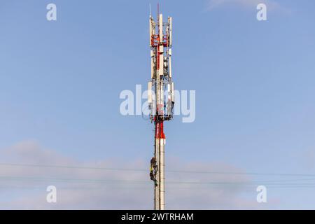 Tecnici che assemblano le antenne per la comunicazione cellulare 5G su una torre di telecomunicazione. Stazione base o stazione base transceiver. Foto Stock