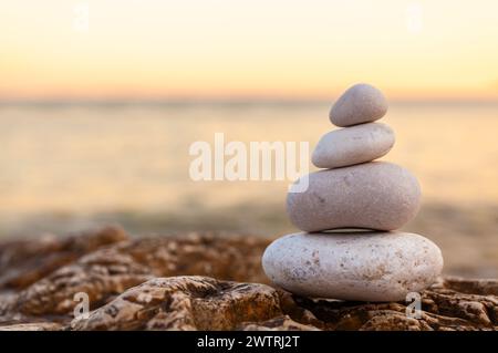 Torre dei pali di pietre sulla cima di una roccia su una tranquilla spiaggia deserta al tramonto di sera Foto Stock