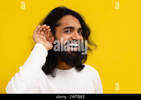 Curioso uomo indiano interessato che si tiene per mano vicino all'orecchio Foto Stock