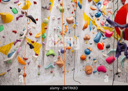 Ripresa interna del centro di arrampicata al coperto senza persone con un assortimento di pareti colorate e impegnative. Parete bianca con rampicanti in g Foto Stock