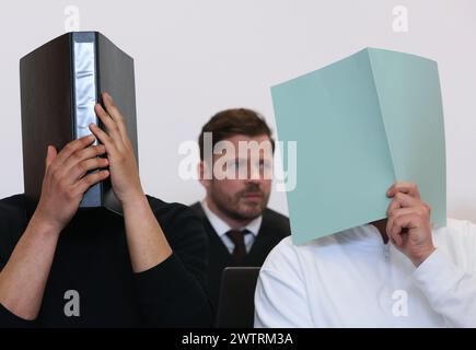 Augusta, Germania. 19 marzo 2024. L'imputato principale (r) siede nel molo in un'aula di tribunale insieme ad altri imputati di fronte all'avvocato Harald Stehr (M). Sta affrontando le accuse di causare l'esplosione di un ordigno esplosivo e causare gravi danni fisici. L'11 novembre 2023, si dice che l'uomo abbia fatto esplodere un firecracker nel blocco visitatori durante la partita di Bundesliga tra FC Augsburg e TSG 1899 Hoffenheim, che non è consentita in Germania. Crediti: Karl-Josef Hildenbrand/dpa/Alamy Live News Foto Stock