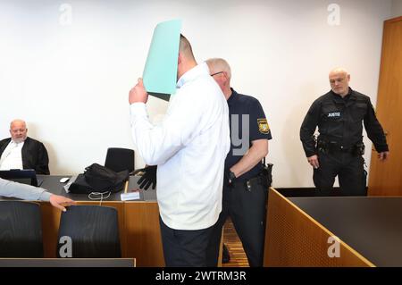 Augusta, Germania. 19 marzo 2024. L'imputato principale (M) è condotto in aula dal personale del tribunale. Sta affrontando le accuse di causare l'esplosione di un ordigno esplosivo e causare gravi danni fisici. L'11 novembre 2023, si dice che l'uomo abbia fatto esplodere un firecracker che non è permesso in Germania durante la partita di Bundesliga tra FC Augsburg e TSG 1899 Hoffenheim nel blocco visitatori. Crediti: Karl-Josef Hildenbrand/dpa/Alamy Live News Foto Stock