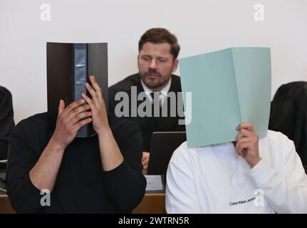 Augusta, Germania. 19 marzo 2024. L'imputato principale (r) siede nel molo in un'aula di tribunale insieme ad altri imputati di fronte all'avvocato Harald Stehr (M). Sta affrontando le accuse di causare l'esplosione di un ordigno esplosivo e causare gravi danni fisici. L'11 novembre 2023, si dice che l'uomo abbia fatto esplodere un firecracker nel blocco visitatori durante la partita di Bundesliga tra FC Augsburg e TSG 1899 Hoffenheim, che non è consentita in Germania. Crediti: Karl-Josef Hildenbrand/dpa/Alamy Live News Foto Stock
