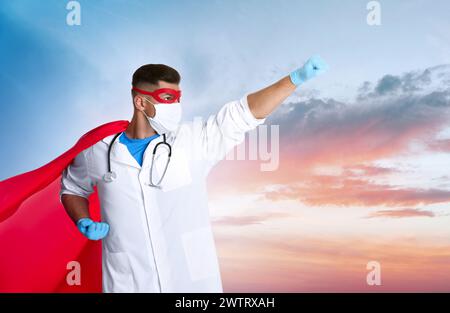 Dottore che indossa maschera viso e costume da supereroe contro il cielo con nuvole, spazio per il testo Foto Stock