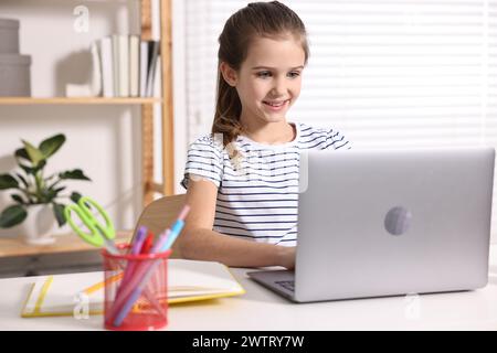 E-learning. Ragazza carina che usa il laptop durante una lezione online al tavolo in casa Foto Stock